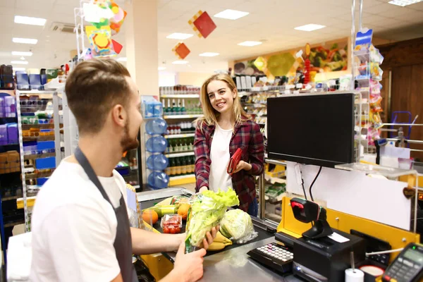 Male cashier checking out goods in supermarket — ストック写真