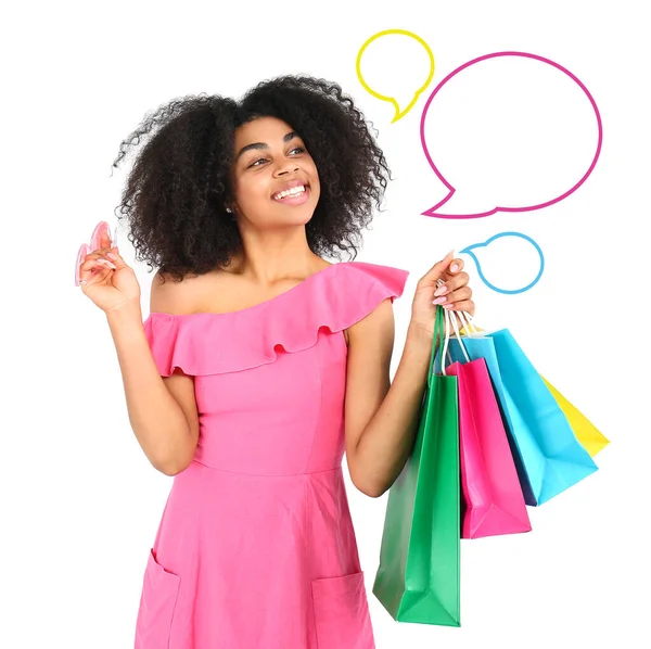 Beautiful African-American woman with shopping bags and blank speech bubbles on white background — ストック写真