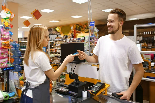 Mladý muž platí za zboží v supermarketu — Stock fotografie