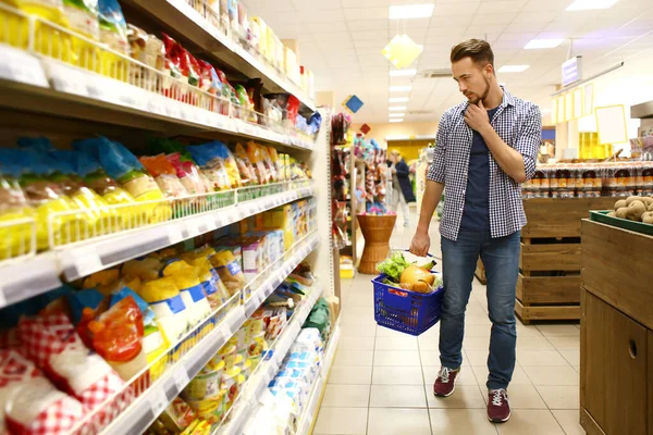 Junger Mann wählt Lebensmittel im Supermarkt — Stockfoto