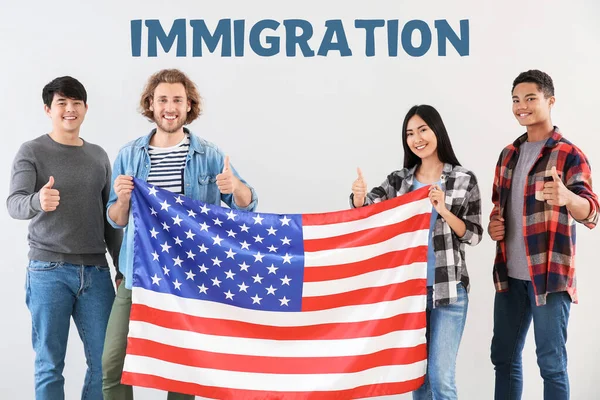 Group of students with USA flag and word IMMIGRATION on light background — Stock Photo, Image