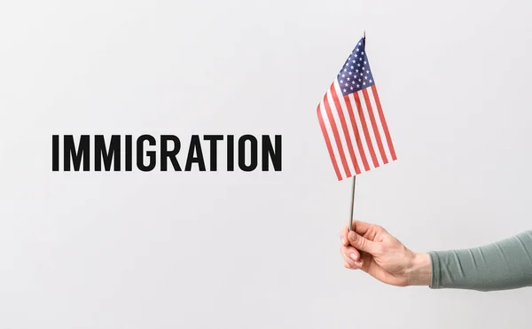 Vrouwelijke hand met Usa vlag en woord Immigratie op lichte achtergrond — Stockfoto