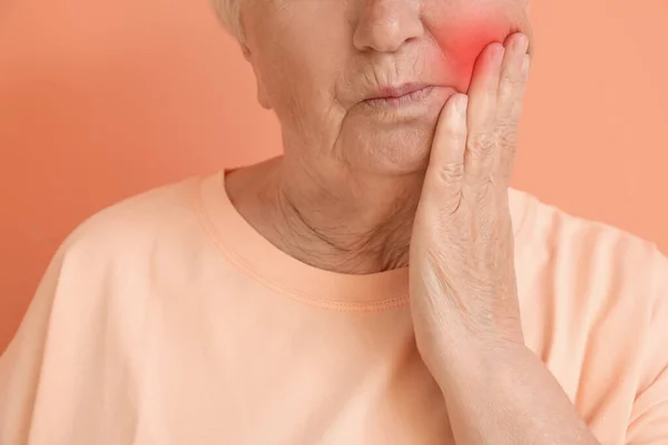 Senior mulher que sofre de dor de dente no fundo de cor, close-up — Fotografia de Stock