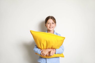 Pijamalı ve hafif arka planda yastığı olan tatlı bir kız.