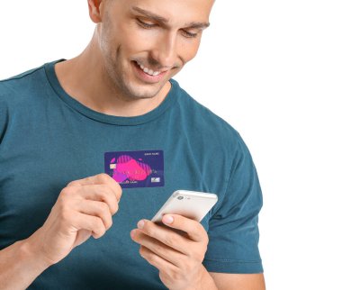 Beyaz arka planda kredi kartı ve cep telefonu ile genç adam