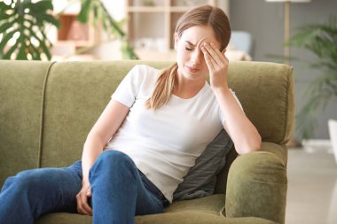 Evde baş ağrısı çeken genç bir kadın.