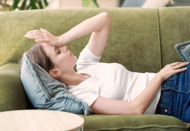 Evde baş ağrısı çeken genç bir kadın.