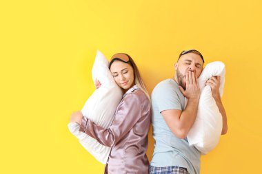 Renkli arka plan üzerinde yastıkile uykulu genç çift