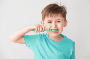 Arka planda diş fırçalayan küçük bir çocuğun portresi