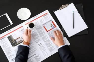 Ofiste gazete okuyan yakışıklı bir iş adamı.