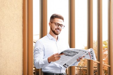 Dışarıda gazetesi olan yakışıklı bir adam.
