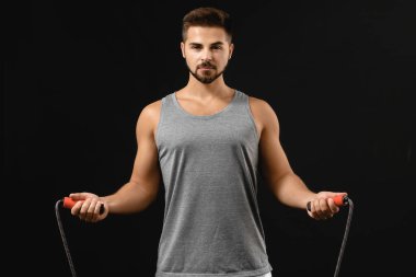 Esmer arka planda ip atlayan genç bir sporcu.