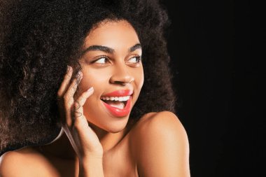 Koyu arkaplanda parlak dudakları olan güzel bir Afro-Amerikalı kadın portresi.