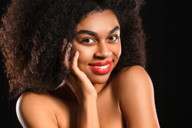 Koyu arkaplanda parlak dudakları olan güzel bir Afro-Amerikalı kadın portresi.