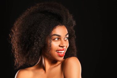 Koyu arkaplanda parlak dudakları olan güzel bir Afro-Amerikalı kadın portresi.