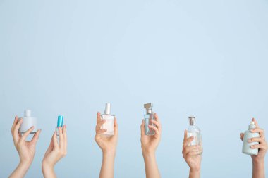 Arka planda farklı parfüm şişeleri olan kadın elleri