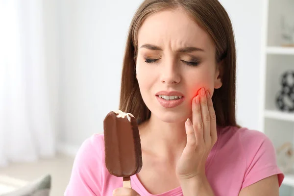 Mujer joven con dientes sensibles y helado frío en casa — Foto de Stock