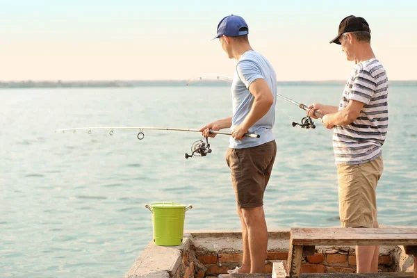 Giovane uomo e suo padre pesca sul fiume — Foto Stock