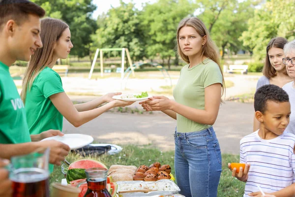 Junge Freiwillige verteilen Lebensmittel an arme Menschen im Freien — Stockfoto