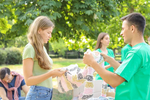 Giovane volontario dando nuovi vestiti per la povera donna all'aperto — Foto Stock