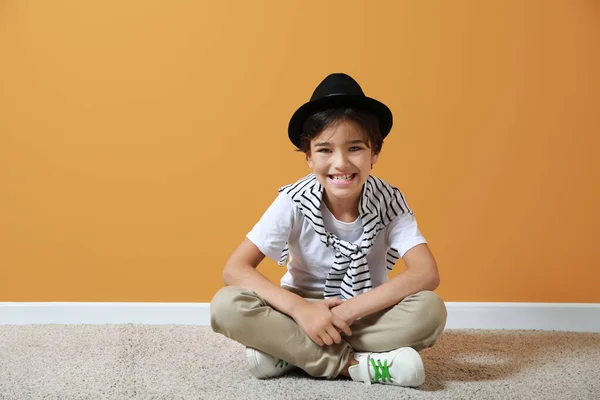 Lindo niño sentado en el suelo cerca de la pared de color —  Fotos de Stock