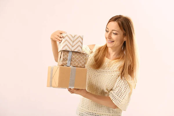 Beautiful woman with gifts on light background — Stock Photo, Image