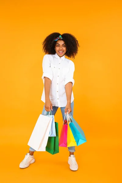 Όμορφη Αφρο-αμερικανική γυναίκα με τσάντες ψώνια στο φόντο χρώμα — Φωτογραφία Αρχείου