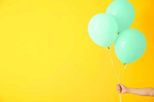 Female hand with air balloons on color background — Stock Photo, Image