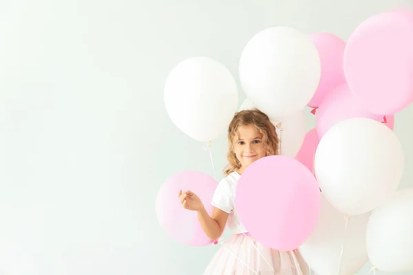 Kleines Mädchen mit Luftballons auf hellem Hintergrund — Stockfoto