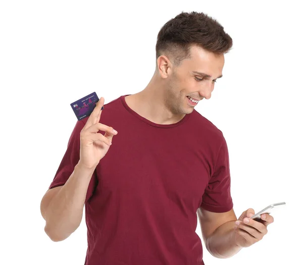 Jovem com cartão de crédito e telefone celular em fundo branco — Fotografia de Stock