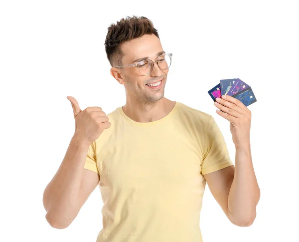 Jovem com cartões de crédito mostrando gesto de polegar para cima no fundo branco — Fotografia de Stock
