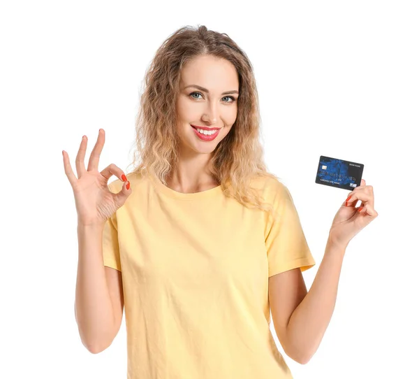 Mujer joven con tarjeta de crédito que muestra gesto OK sobre fondo blanco — Foto de Stock