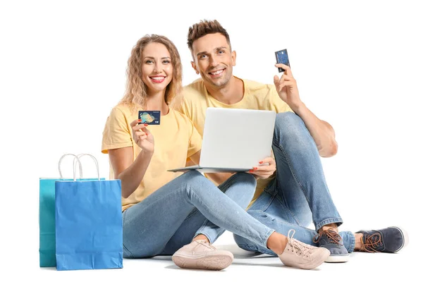 Fiatal pár hitelkártyák, bevásárló táskák és laptop fehér háttér — Stock Fotó