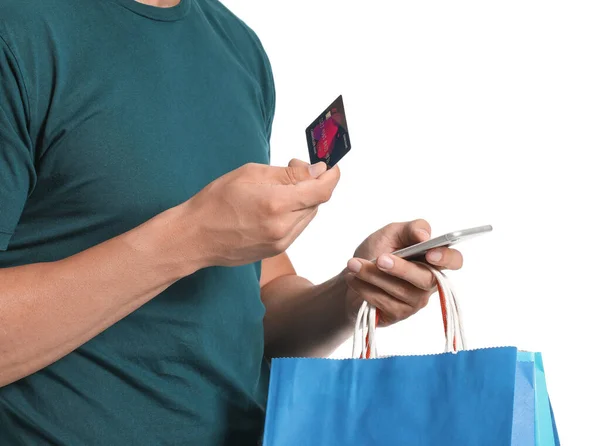 Young man with credit card, shopping bags and mobile phone on white background — Stock Photo, Image