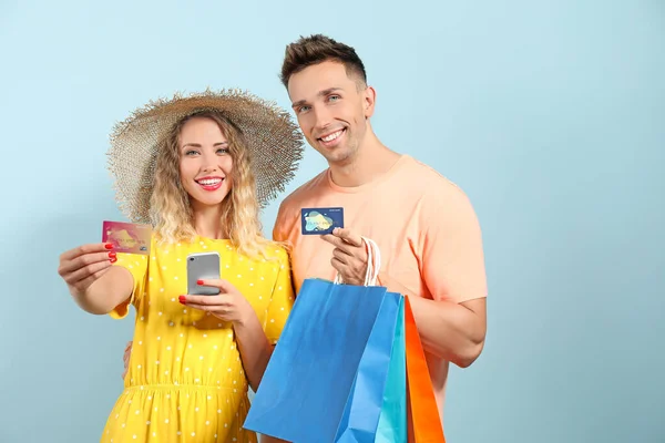 Молода пара з кредитними картками, сумками для покупок та мобільним телефоном на кольоровому фоні — стокове фото
