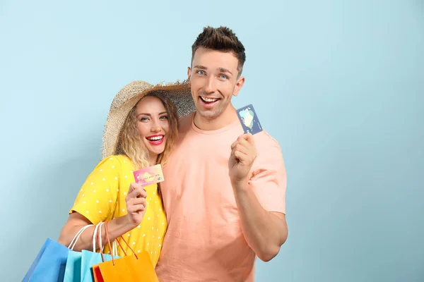 Fiatal pár hitelkártyák és bevásárló táskák színes háttér — Stock Fotó