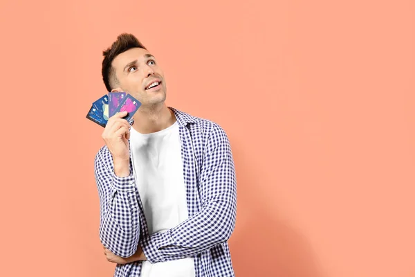 Young man with credit cards on color background — Stock Photo, Image