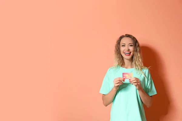 Mladá žena s kreditní kartou na barevném pozadí — Stock fotografie