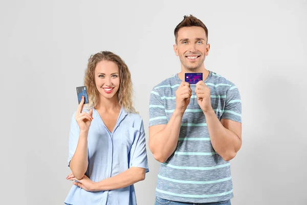 Young couple with credit cards on light background — Stock Photo, Image