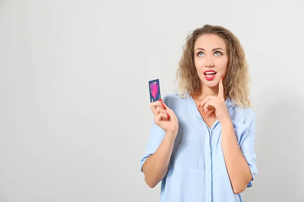 Gedachte vrouw met creditcard op lichte achtergrond — Stockfoto