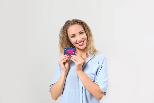 Jonge vrouw met credit card op lichte achtergrond — Stockfoto