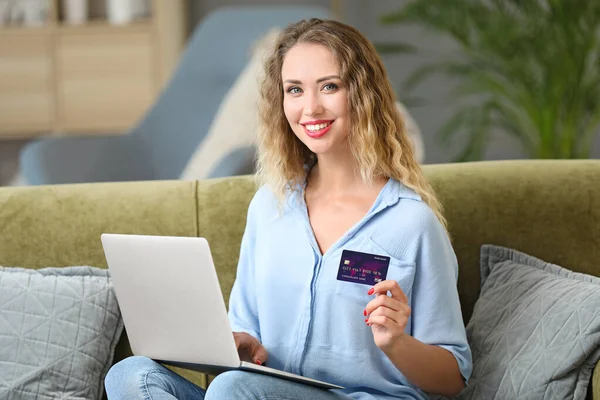 Jeune femme avec carte de crédit et ordinateur portable à la maison — Photo