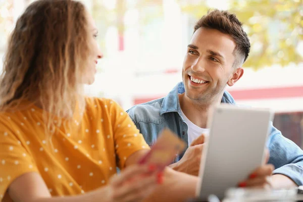 Casal jovem com cartão de crédito e tablet sentado no café — Fotografia de Stock