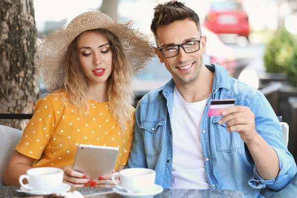 Jeune couple avec carte de crédit et tablette assis dans un café — Photo