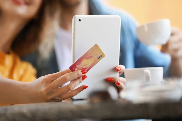 Jeune femme avec carte de crédit et tablette d'ordinateur assis dans le café, gros plan — Photo