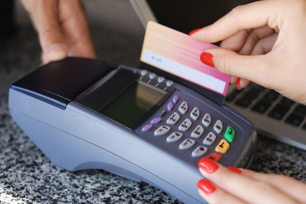 Young woman paying by credit card in cafe, closeup