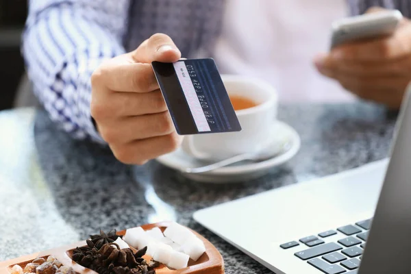 Young man with credit card sitting in cafe, closeup — Stock Photo, Image