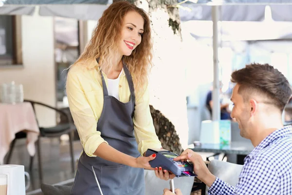 Young man paying by credit card in cafe — Stock Photo, Image