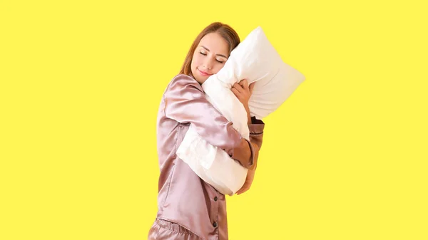 Beautiful young woman with pillow on color background — Stock Photo, Image