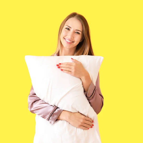 Beautiful young woman with pillow on color background — Stock Photo, Image